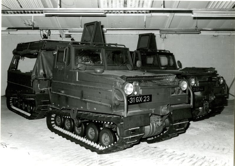 Black and white photograph of a tracked vehicle with tracked trailer on the back.