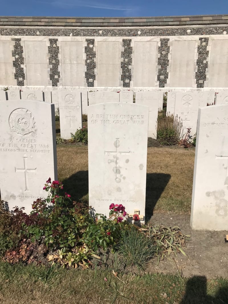 Image shows rows of white CWGC style headstones and the memorial wall behind.