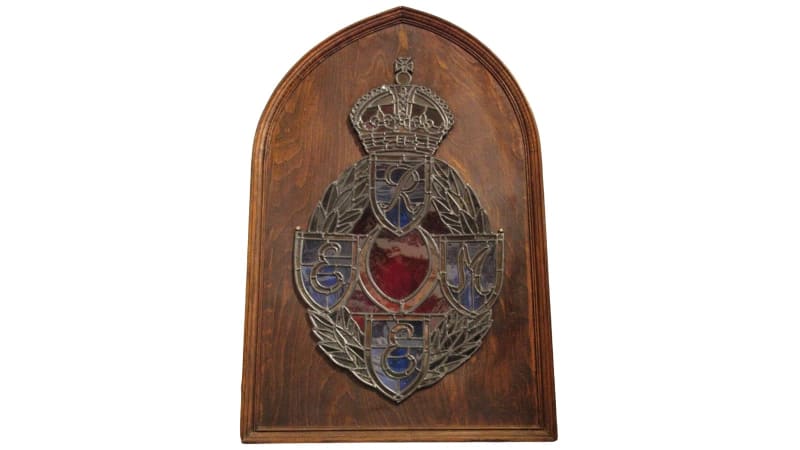 A wooden filled arch with stained glass REME cap badge in the centre.