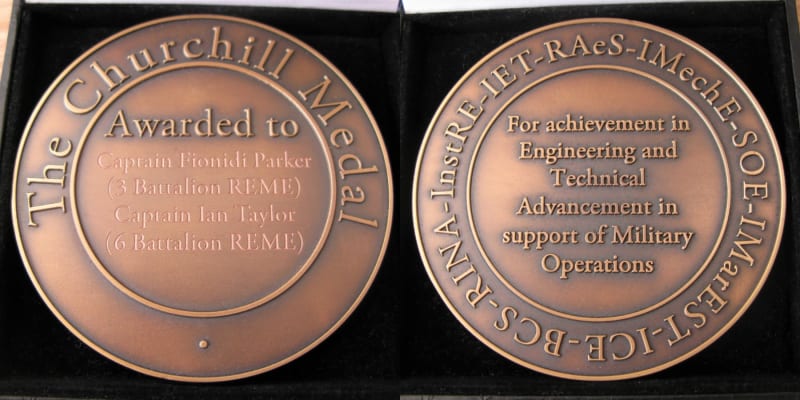Two sides of a bronze coloured circular medallion with embossed writing.