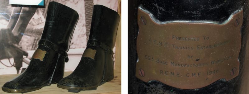 Two images. Left, a pair of black boots made from metal, each with a small plaque. Right, a close-up of the plaque.