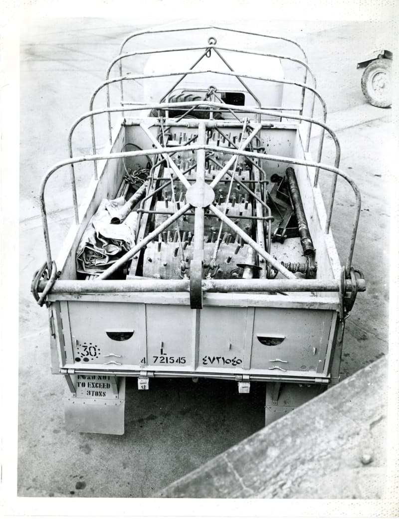 Image shows the rear of an open top truck from an aerial view. There are spikey rollers in the truck.