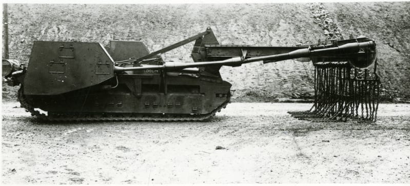 Side view of a tank with crane at the front and roller device, chains hanging off the roller.