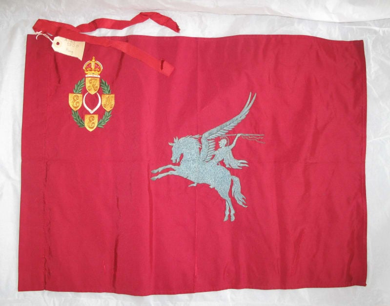 Red flag with first pattern REME badge in top left corner, pale blue Pegasus ridden by a soldier in the centre.