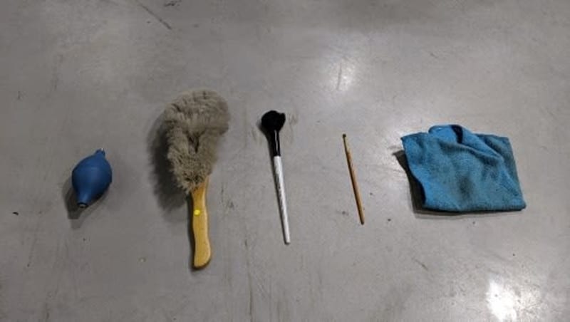 Cleaning brushes of various sizes and a blue microfibre cloth laid out on a plain surface.