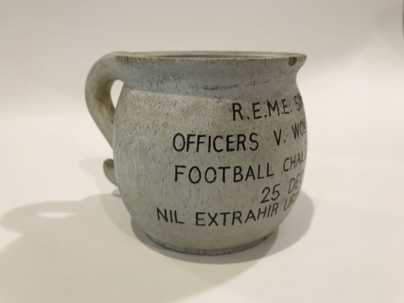 Stone chamber pot with black text on the front. The pot is photographed from the side so only part of the text is visible.