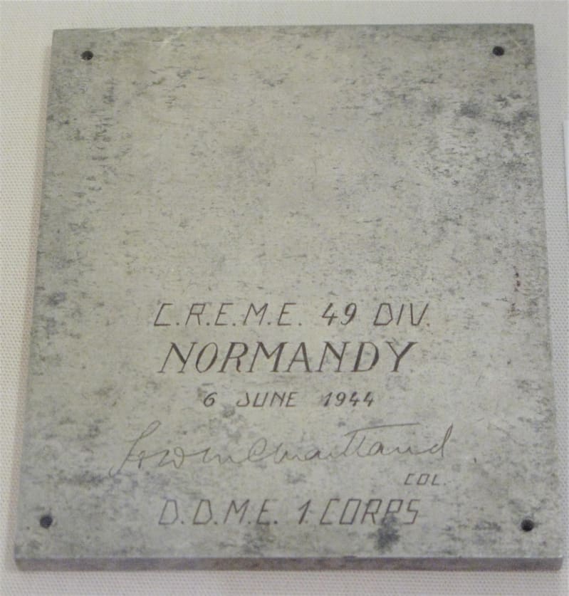 A square piece of silver colour metal, engraved with C.R.E.M.E 49 Div, Normandy 6 June 1944 and signed by DDME 1 Corps.