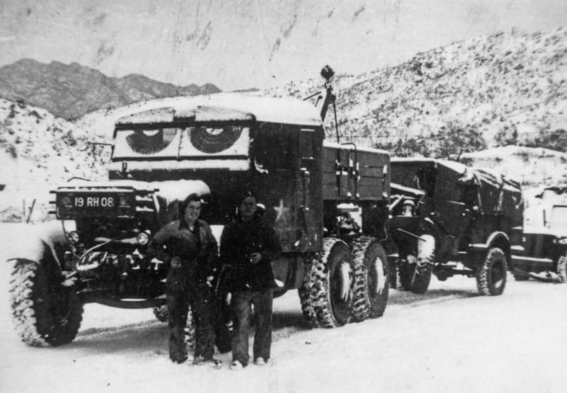 Black and white photograph of a vehicle towing another vehicle along a snowy landscape.