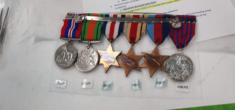 Image shows medals with stickers removed below, some of the medals have tarnished surfaces